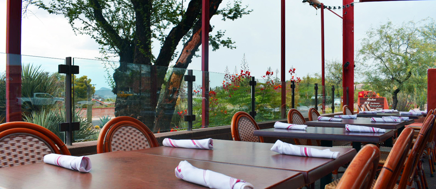 Set tables on the glass-enclosed patio at Confluence with desert views